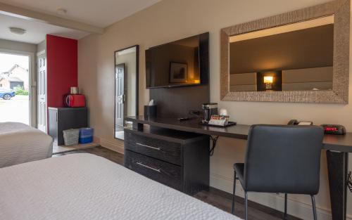 a bedroom with a desk and a bed and a mirror at Ramada by Wyndham Ottawa On The Rideau in Ottawa
