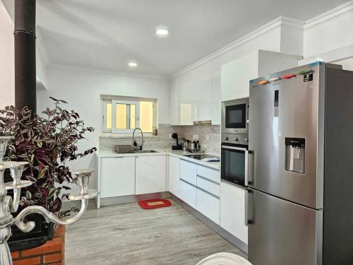 a kitchen with a stainless steel refrigerator and white cabinets at House of Belverde with Pool in Amora