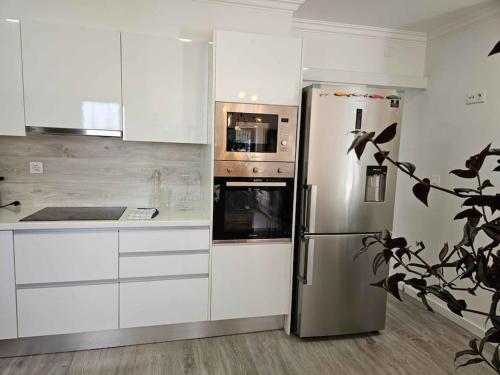 a stainless steel refrigerator in a kitchen with white cabinets at House of Belverde with Pool in Amora
