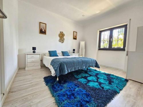 a bedroom with a bed and a blue rug at House of Belverde with Pool in Amora
