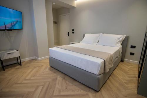 a bedroom with a bed with white sheets and a flat screen tv at Mina Luxury Rooms in Tirana