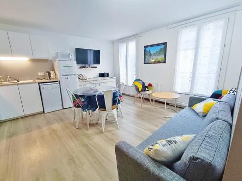 a living room with a blue couch and a kitchen at Résidence des Jardins, wifi, centre Luchon in Luchon
