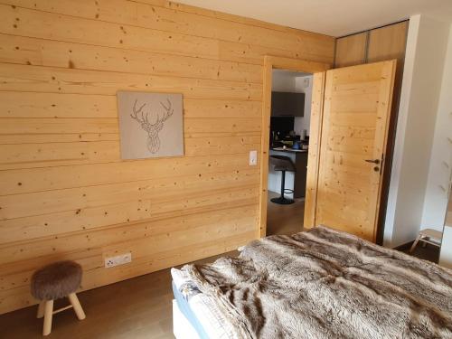 a bedroom with a wooden wall with a bed and a chair at Perle de Savoie Free multipass offer for 4 guests in Châtel