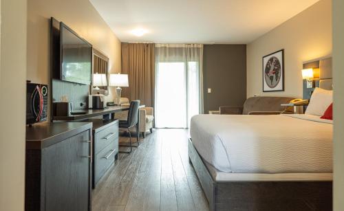 a hotel room with a bed and a desk with a television at Ramada by Wyndham Ottawa On The Rideau in Ottawa