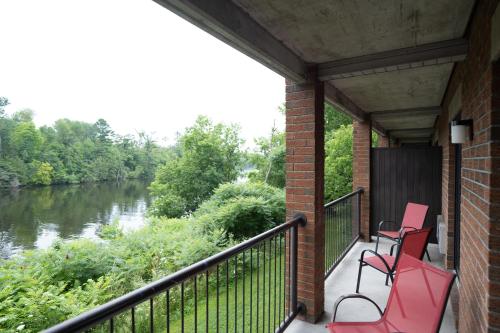 two red chairs sitting on a balcony next to a river at Ramada by Wyndham Ottawa On The Rideau in Ottawa