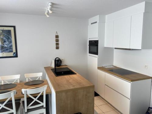 une cuisine avec des armoires blanches et une table et des chaises dans l'établissement Zonnekring 0903, à Nieuport