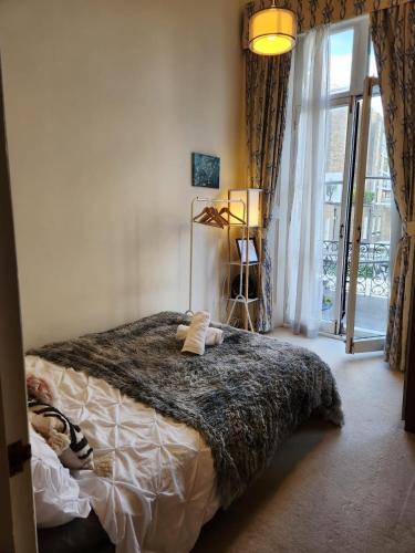 a bedroom with a bed and a large window at Cosy High-ceiling Victorian flat with balcony - 2mins to Hyde Park, Kensington Palace, NottingHill, High Street Kensington,2BR 2Baths in London