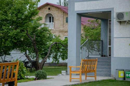 two wooden benches sitting outside of a house at Hotel Good Night in Jalal-Abad