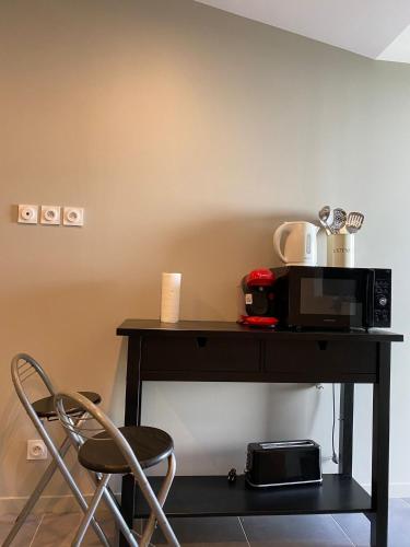 une table avec un micro-ondes et une chaise dans l'établissement Le charmant studio, à Baillargues