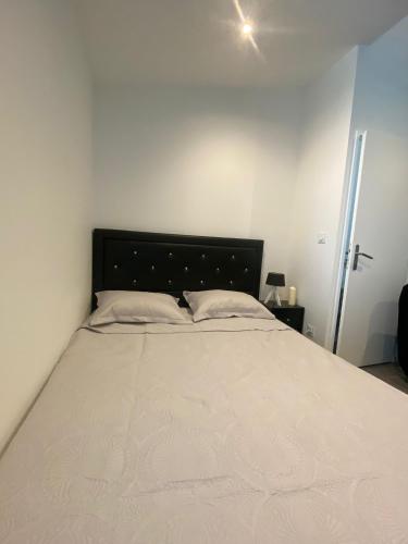 - une chambre avec un grand lit et un couvre-lit blanc dans l'établissement Le charmant studio, à Baillargues