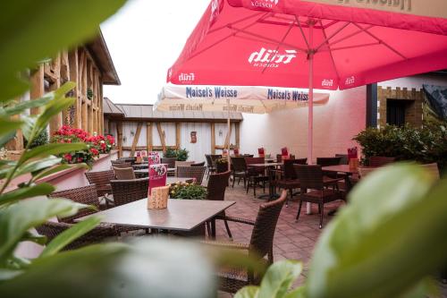 a restaurant with tables and chairs and a red umbrella at Gasthaus Stroh in Buchholz