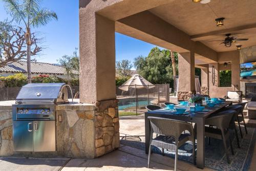 an outdoor kitchen with a table and a grill at Casa Serenity - Luxury Living w Pool & Jacuzzi in Indio
