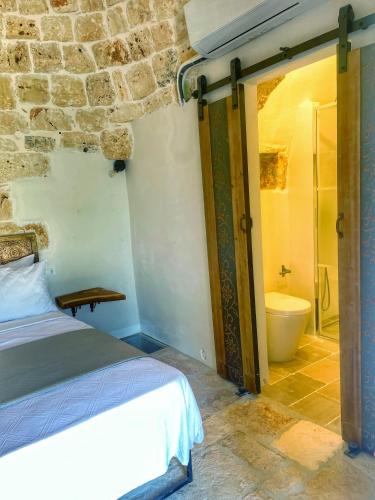 a bedroom with a bed and a bathroom with a toilet at Trullideserio in San Michele Salentino