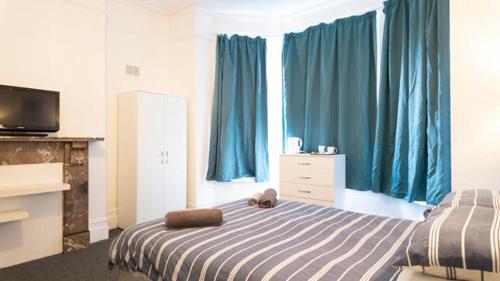 a bedroom with a bed and a window with blue curtains at Pebbles guest house room 11 in Southampton