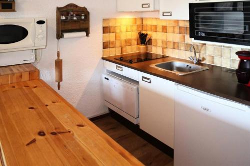 une petite cuisine avec un évier et un micro-ondes dans l'établissement Résidence Le Cairn - 1010 CAIRN LES ORRES 1650 MAE-0934, aux Orres