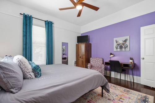 ein Schlafzimmer mit lila Wänden und einem Bett und einem Schreibtisch in der Unterkunft Vineyard Cottage-Pet Friendly & Walk to Oaklawn! in Hot Springs