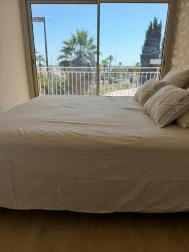 une chambre avec un grand lit avec une grande fenêtre dans l'établissement Appartement face au port, à Antibes
