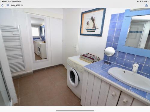 une salle de bain avec une machine à laver et un lavabo dans l'établissement Maison à la plage, à Canet