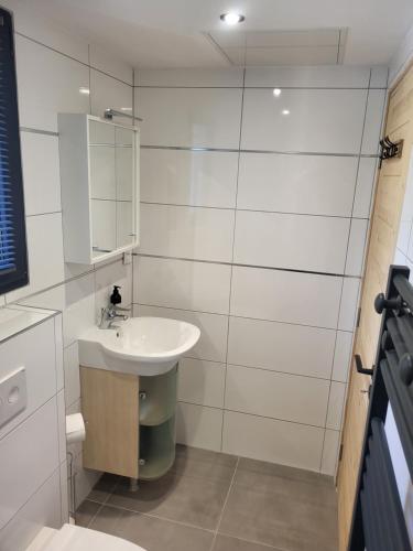 une salle de bain blanche avec un lavabo et un miroir dans l'établissement Studio Saint Antoine Les Houches, aux Houches