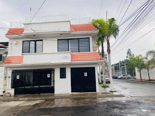 a white house with an orange roof and a palm tree at Casa Independencia in Santa Julia