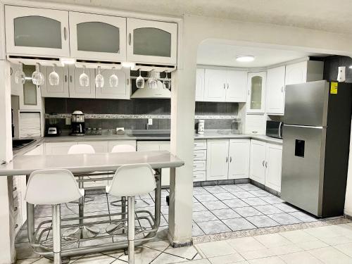 a kitchen with white cabinets and a table and a refrigerator at Casa Independencia in Santa Julia