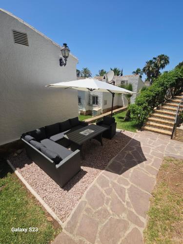 a patio with a black couch and an umbrella at Villa Adriana v rezidencii Toscamar in Jávea