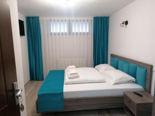 a bedroom with a bed with blue and white sheets at Casa Vânătorilor in Arieşeni