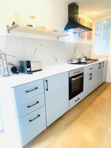 La cuisine est équipée de comptoirs blancs et de plaques de cuisson. dans l'établissement Le Cézembre Nouveauté 2024 H&F, à Dinard