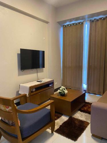 a living room with a tv and a chair and a couch at Mactan Newtown Beach Condo in Mactan