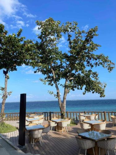 a patio with tables and chairs and the ocean at Mactan Newtown Beach Condo in Mactan