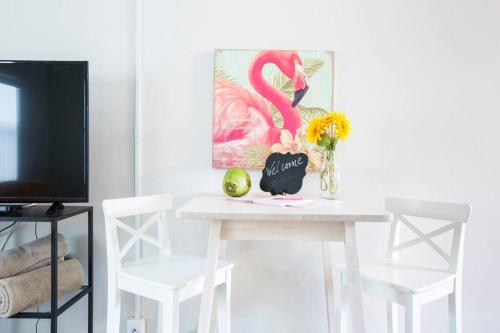a white table with a vase of flowers and a pink flamingo at Studio in Pompano Beach two blocks from the Ocean in Pompano Beach