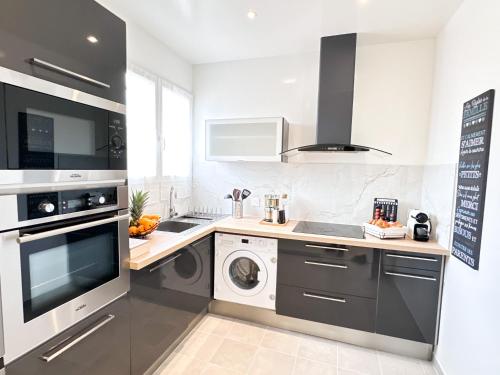 une cuisine équipée d'un lave-linge et d'un lave-linge/sèche-linge. dans l'établissement Appartement Cosy proche PARIS, à Aulnay-sous-Bois