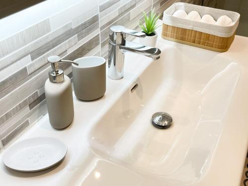 - un lavabo dans la salle de bains avec deux distributeurs de savon dans l'établissement Appartement Cosy proche PARIS, à Aulnay-sous-Bois