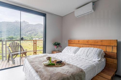 Un dormitorio con una cama grande y un balcón. en Cabana do Lago - Villas Mornas Natureza e Jacuzzi, en Aguas Mornas