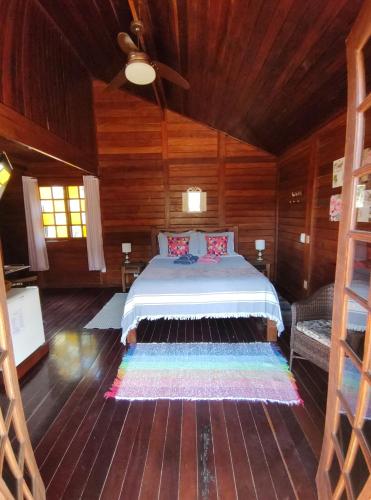 a bedroom with a bed in a wooden room at Chalés Nó da Madeira in Visconde De Maua