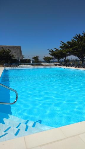 une grande piscine avec de l'eau bleue dans l'établissement Charmant logement Guidel Plage, vue mer, piscine chauffée, avec une chambre, à Guidel