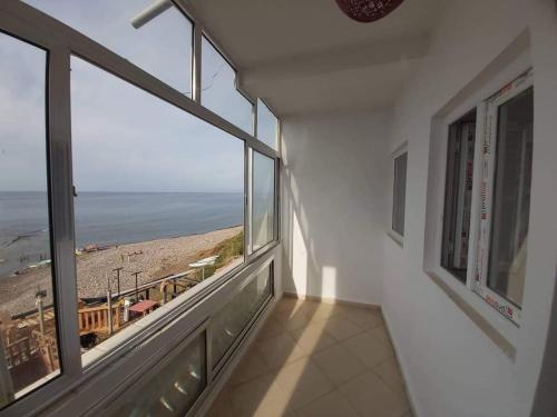 a room with large windows with a view of the beach at Residence balnéaire TADHRIHTH in Irhil Khelil