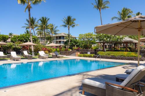 a swimming pool with chairs and an umbrella at Hilton Pool Pass Included, Kolea - Luxe Penthouse, Walk to Beach in Waikoloa