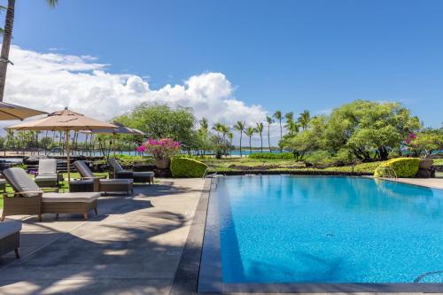 a pool at a resort with chairs and umbrellas at Hilton Pool Pass Included, Kolea - Luxe Penthouse, Walk to Beach in Waikoloa