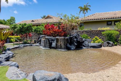 a pond with a waterfall in front of a house at Hilton Pool Pass Included, Kolea - Luxe Penthouse, Walk to Beach in Waikoloa
