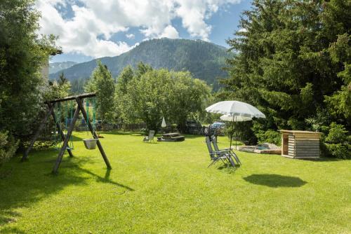a park with a swing set and an umbrella at Chesa-strimer - Rustica in La Punt-Chamues-ch