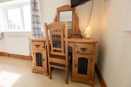 a wooden dressing table with a chair and a mirror at Mountain View in Moelfre