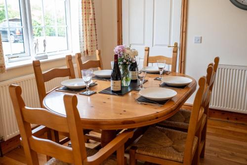a dining room table with chairs and a wooden table with flowers at Mountain View in Moelfre