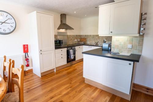 a kitchen with white cabinets and a clock on the wall at Mountain View in Moelfre