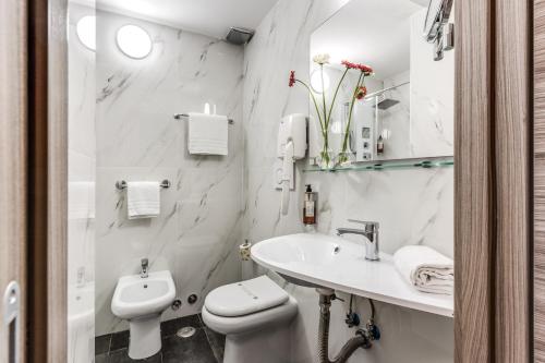 a white bathroom with a toilet and a sink at Hotel Centro Cavour Roma in Rome