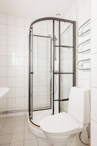 a white bathroom with a shower and a toilet at Large Central Gothenburg 2bd Apt in Gothenburg