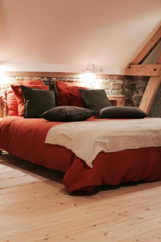 une chambre avec un grand lit avec des draps et des oreillers rouges dans l'établissement Duplex accès jacuzzi illimité, à Villedieu-les-Poêles