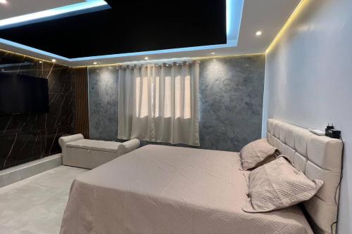 a bedroom with a large bed and a television at Suíte Gold Cinema 303 in Santo Antônio do Descoberto