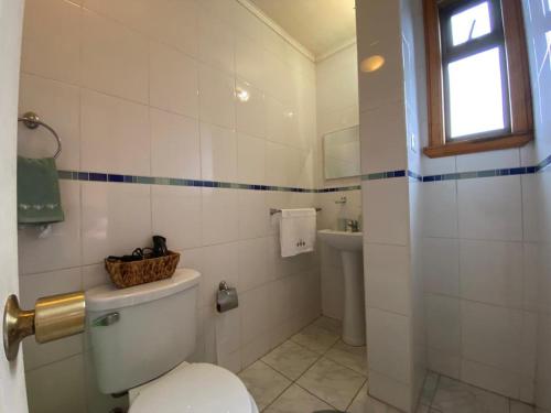 a white bathroom with a toilet and a sink at Hospedaje Casa Mirador in Puerto Montt