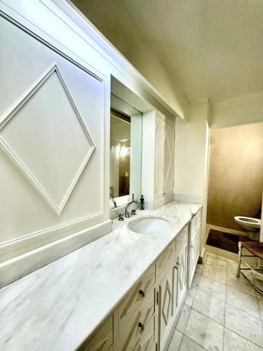 une salle de bain blanche avec un lavabo et un miroir dans l'établissement Beautiful flat in Saint-Germain, à Paris